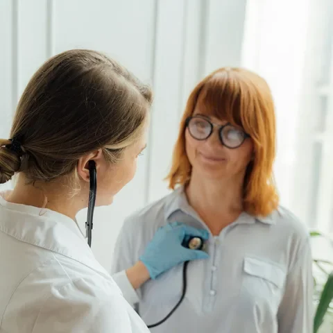 A physician listening to a patient&rsquo;s heart with a stethoscope